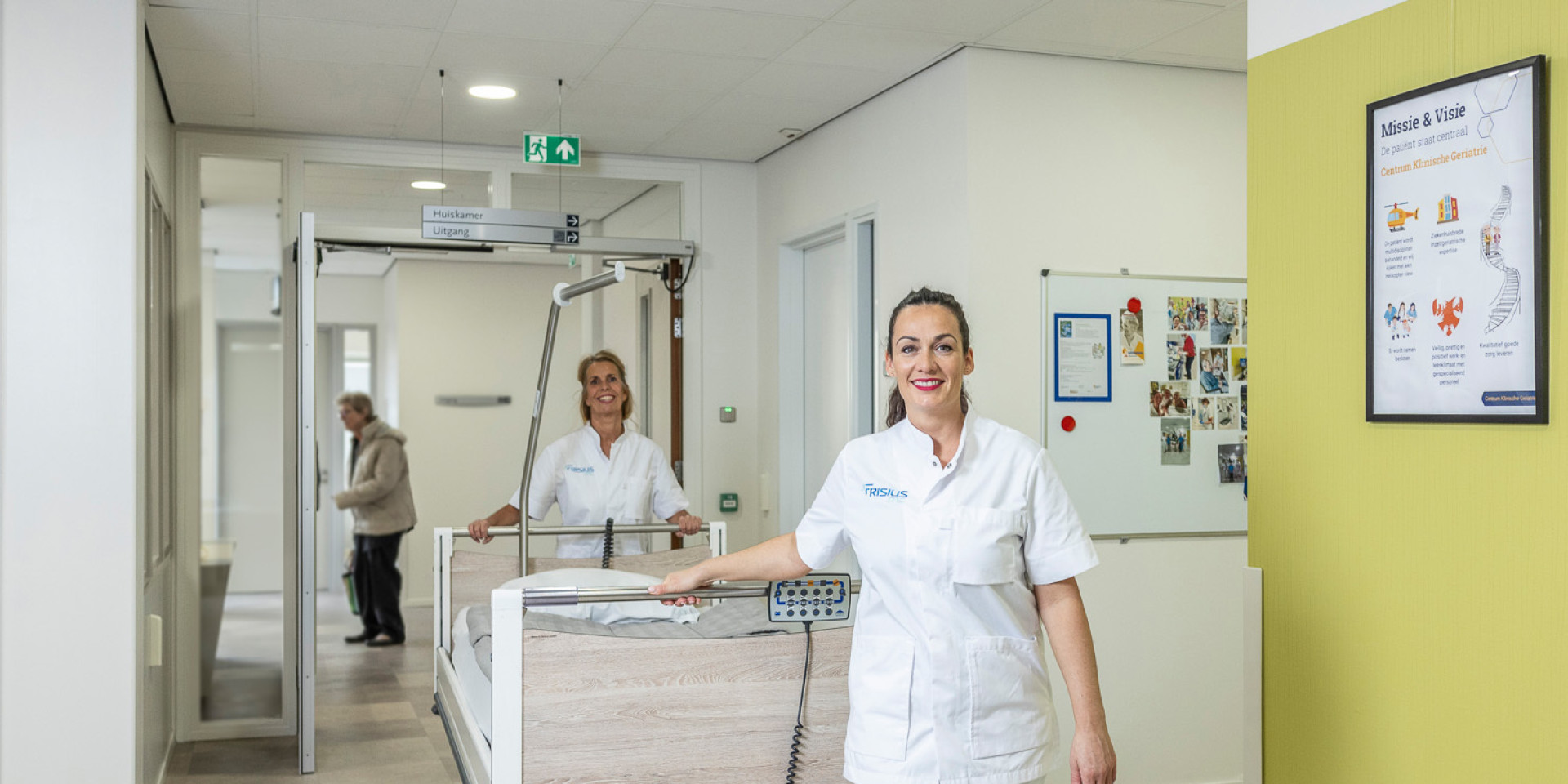 Twee verpleegkundigen van Frisius MC duwt een bed door de gang van het ziekenhuis